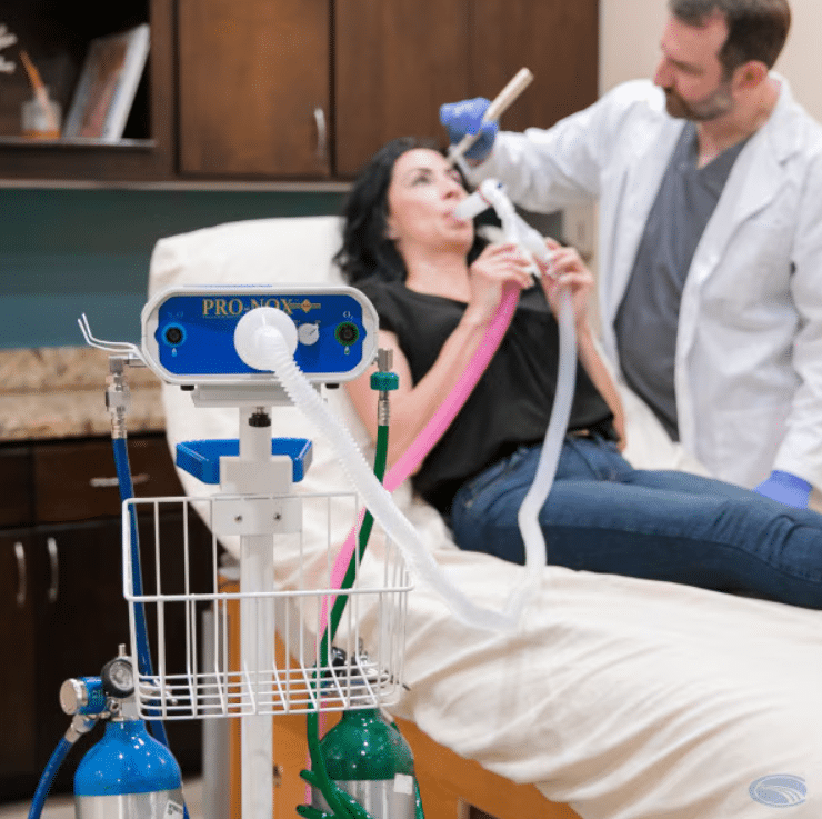 Aesthetic doctor preparing Pro-Nox Carestream device for pain management before a microneedling procedure.