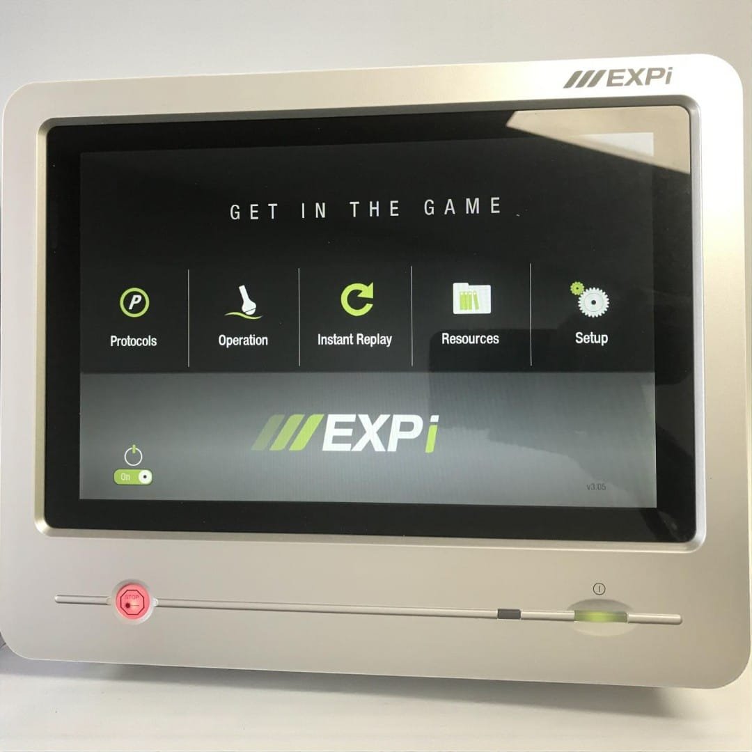 A close-up view of the LightForce EXPi 25 Watt laser therapy device interface and main menu. LightForce EXPi 25W therapy laser device touchscreen showing main menu icons including Protocols, Operation, and Instant Replay